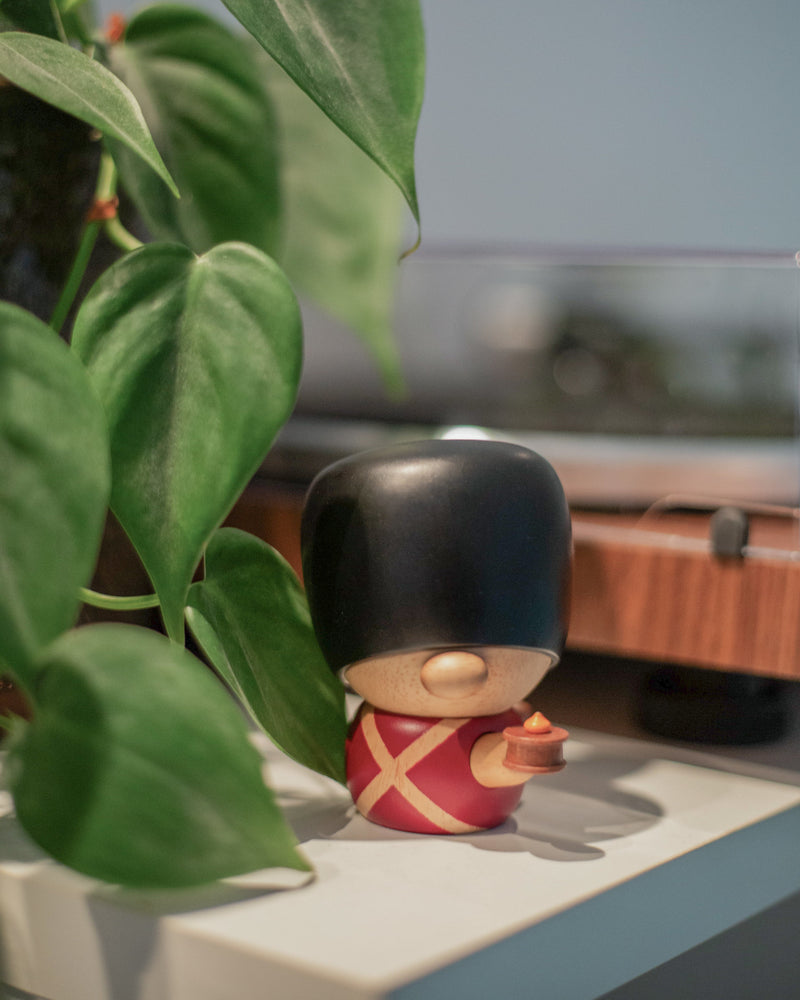 
                  
                    Miljøbillede af Fyrtøjet figuren. Den står i en stue ved siden af en plante som dekoration. 
                  
                